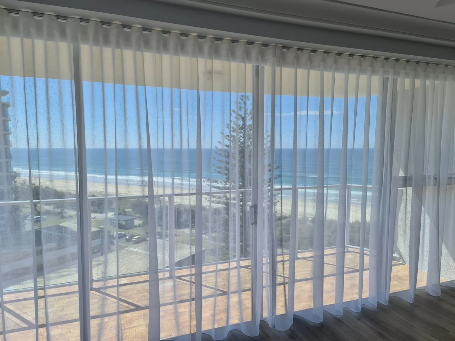 Sheer curtains opening to a Southport beach balcony view