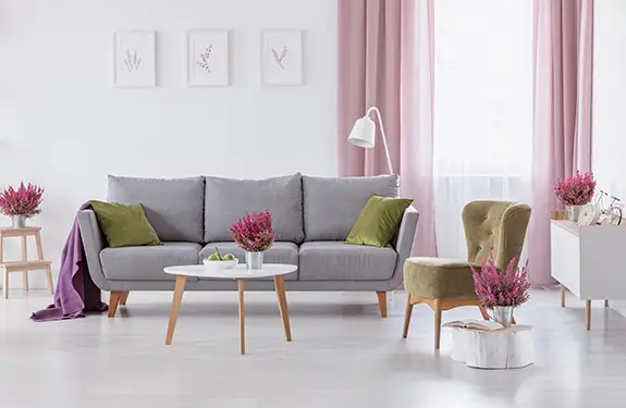 Soft pink curtains in a bright living room with a grey sofa