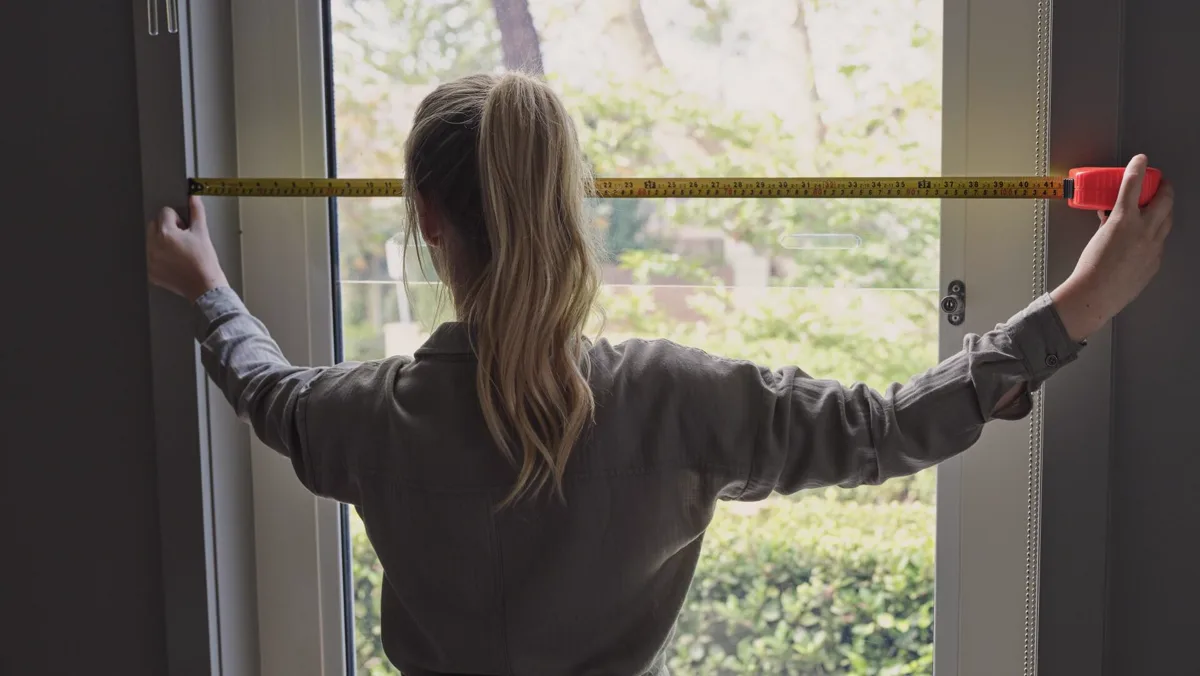 Window width being measured with a tape measure before custom curtains are made