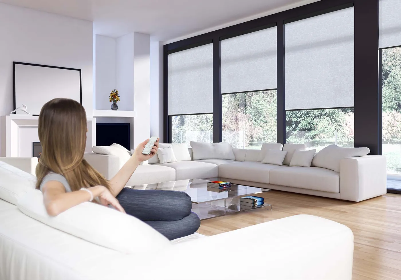 Woman using a remote to control motorised roller blinds across wide living-room windows
