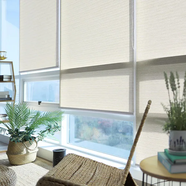 Three light-filtering roller blinds softening sunlight across large living room windows