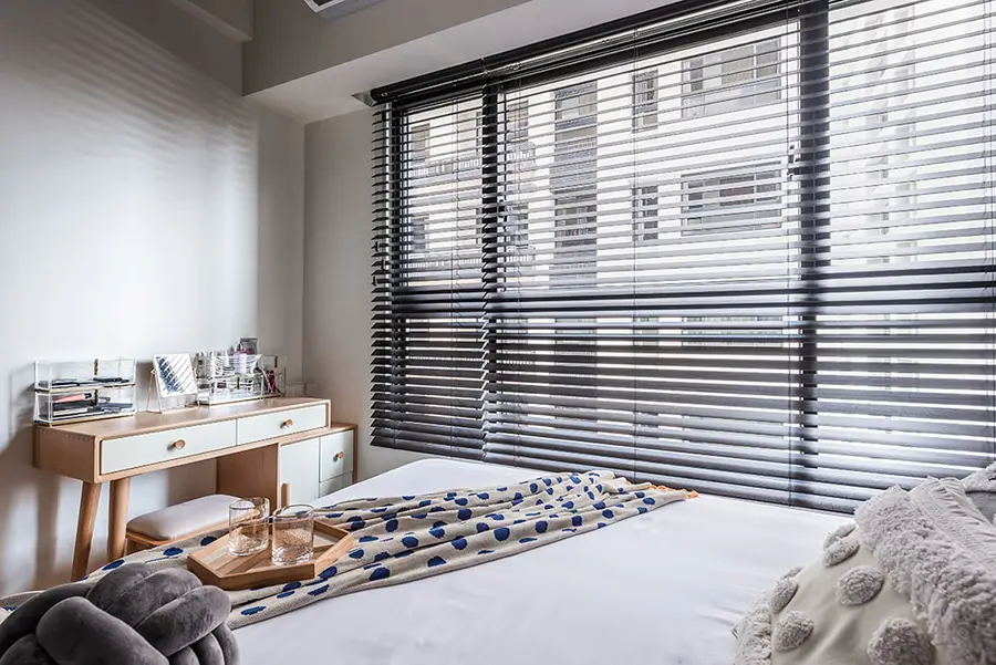 Dark Venetian blinds across a large bedroom window in a modern apartment