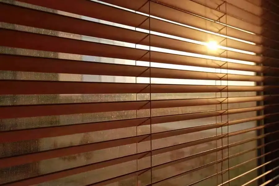 Close-up of Venetian blind slats with warm sunlight filtering through