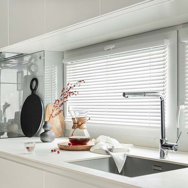 White Venetian blinds installed over corner kitchen windows with timber cabinetry