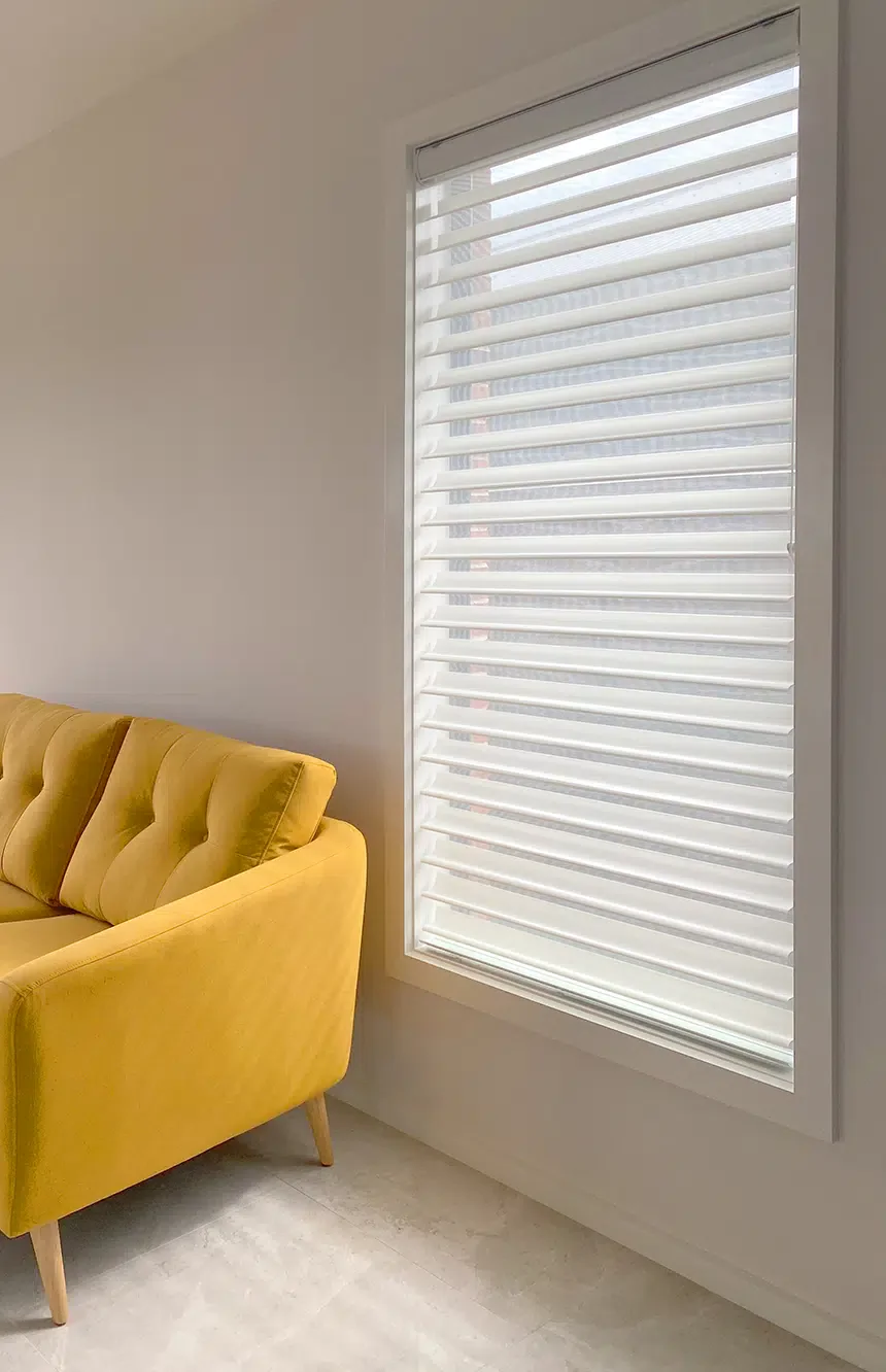 Open white Venetian blinds beside a mustard armchair in a Gold Coast living room